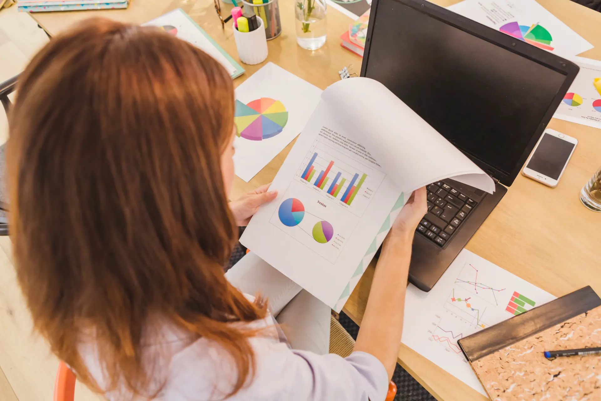 Pessoa analisando gráficos e tabelas financeiros em uma mesa de trabalho com documentos, calculadora e computador, ilustrando deságio precatório 2026 e pagamento por empresas.