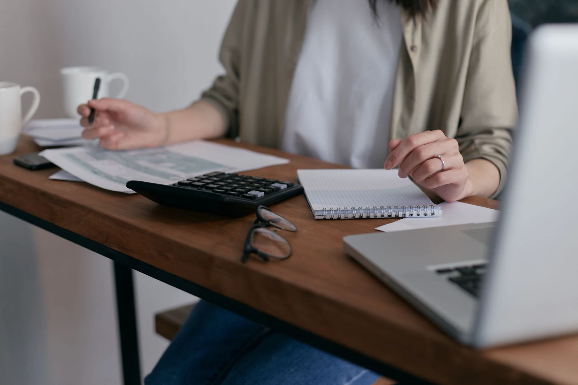 Pessoa em ambiente de escritório analisando documentos e anotações sobre imposto de renda, com calculadora, notebook e caneta sobre a mesa. Como Declarar a Venda de Precatório no Imposto de Renda.